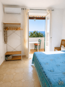 Il piccolo balcone vista vigneto e mare, arredato con tavolo esedie per due racconta il ritmo lento della vacanza - La quercia di Villa Olivia, ischia