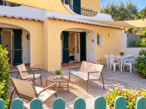 Terrazza del Nespolo a Villa Olivia, Forio d'Ischia, con zona pranzo all'aperto, salottino relax, vele ombreggianti e giardino mediterraneo